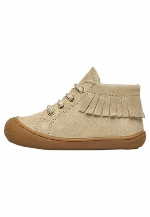 Beige suède peutersneaker met bruine rubberen zool, vetersluiting aan de voorkant en decoratieve franjes rond de enkelkraag.