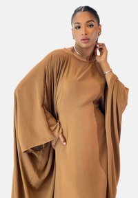 Braunes, übergroßes Kleid mit weitem Ärmel, gefertigt aus leichtem Stoff. Einfaches, einfarbiges Design mit entspannter Silhouette und minimalen Akzenten.