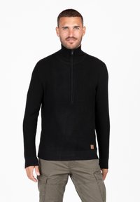 Maglione nero in maglia con colletto alto e mezza cerniera. Presenta polsini e orlo a coste, con un piccolo etichetta marrone in basso a sinistra.