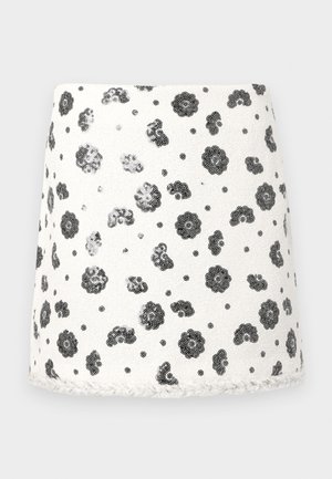 Bijela suknja od tkanine s crnim cvjetnim uzorkom i uzdignutim teksturiranim detaljima. Rub ima teksturirani rub. Kratki A-oblika.