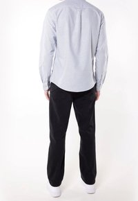 Męska koszula z długim rękawem w niebiesko-białe paski, zestawiona z czarnymi spodniami. Posiada kołnierzyk, mankiety na guziki oraz zaszewki z tyłu.