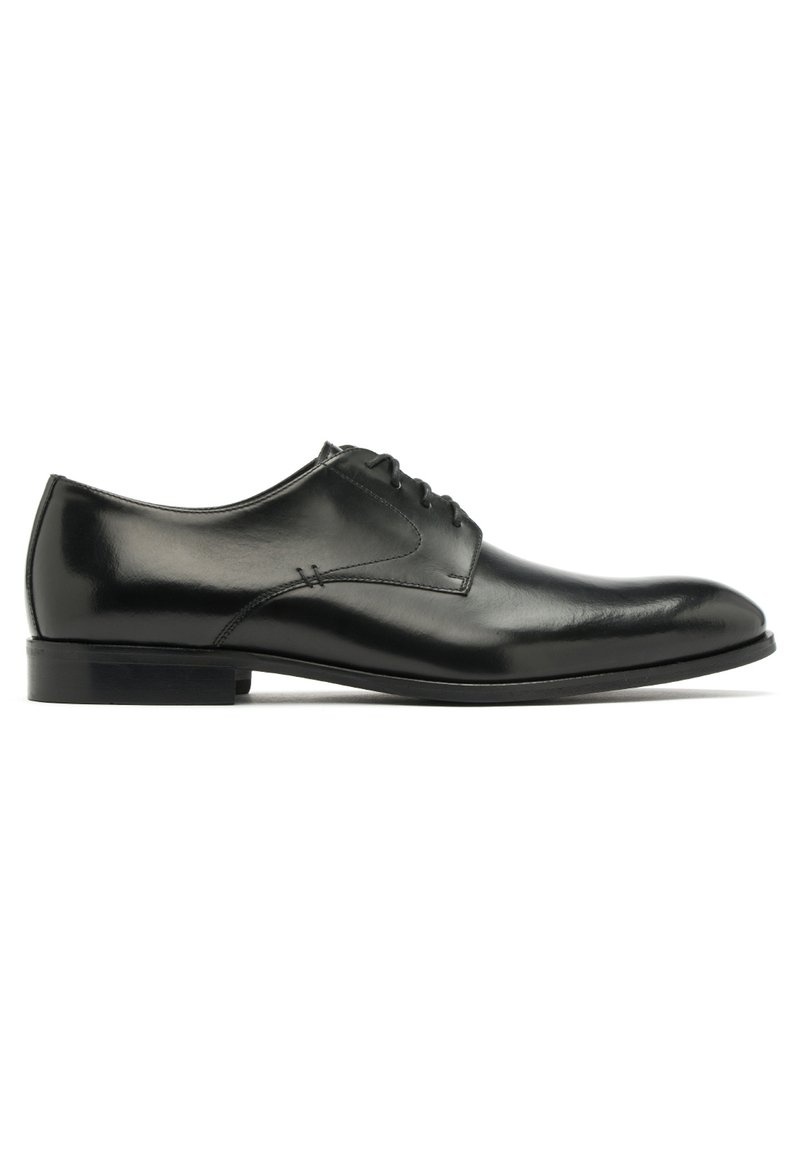 Chaussure habillée en cuir noir avec une finition lisse, un bout arrondi et six œillets pour les lacets. Dispose d'un petit talon et de détails de couture discrets.