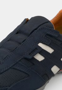 Navy sneaker with mesh panels, suede texture, white accents, and a rubber sole. Features the "GEOX" logo on the side.