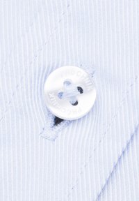 Jasnoniebieska materiał w paski z białym guzikiem z czterema otworami i wytłoczonym tekstem. Widoczne szwy w pobliżu dziurki guzikowej.