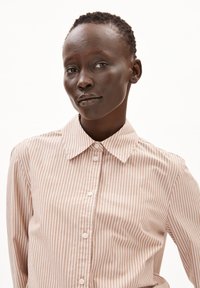 Camicia a righe rosa chiaro con colletto classico e texture liscia, caratterizzata da una serie di bottoni coordinati lungo la parte anteriore.