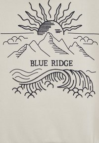 Crèmekleurige sweatshirt met marineblauwe borduursels van bergen, een zon en golven, met de tekst "BLUE RIDGE" centraal gepositioneerd.