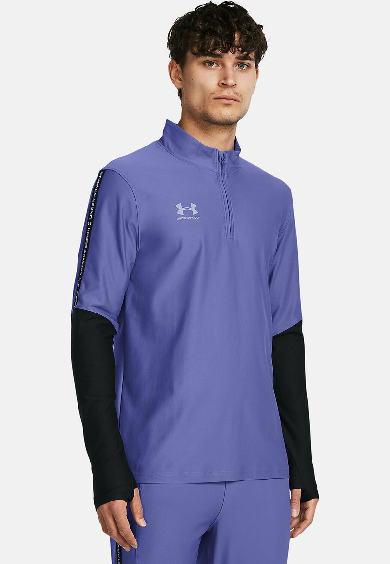 Lila Sport-Zipshirt mit schwarzen langen Ärmeln, leichtem Stoff, Logo auf der Brust und kontrastierenden Streifen an den Ärmeln.