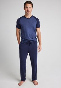 Marinblå pyjamasset som består av en kortärmad topp med v-ringning och raglanärmar, ihopparat med byxor med dragsko i ett mjukt och slätt tyg.