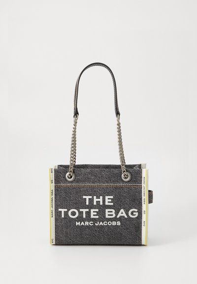 Geantă tote din denim gri închis Marc Jacobs, cu mânere din lanț și piele, text alb "THE TOTE BAG MARC JACOBS" pe panoul din față.