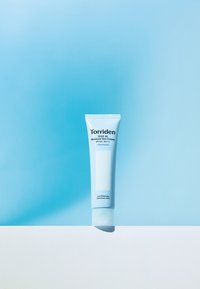 Torriden Dive In Moisture Solcreme tube, plastisk, lys blå med hvide detaljer, som viser tekst og en glansfuld finish på en hvid overflade.