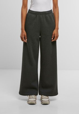 Ciemnoszare, szerokie spodnie dresowe z elastycznym pasem, wykonane z miękkiego materiału. Pasują do butów sportowych w neutralnych kolorach.