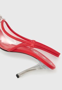 Κόκκινο ψηλοτάκουνο σανδάλι με διαφανές λουράκι και τακούνι, με υφή κόκκινης σόλας και λεπτό υφασμάτινο λουράκ ι στον αστράγαλο.