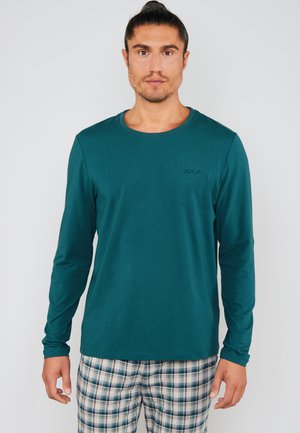 Long-sleeve teal shirt with a round neckline and a small embossed logo. Paired with checkered plaid pants in blue, white, and green tones.