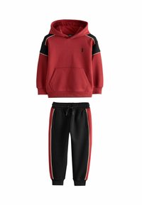 Rød hættetrøje med sorte skulderdetaljer og en frontlomme, parret med sorte sweatpants med røde sidelænd og en elastisk talje.