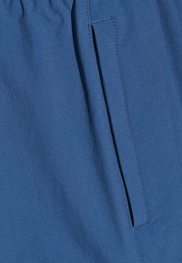 Blått tyg med en jämn yta, med en sidoficka. Midjebandet är elastiskt, vilket ger en avslappnad passform och en avslappnad design.