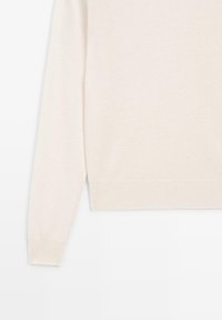 Ljusbeige tröja med mjuk textur, långa ärmar, ribbstickade muddar och fåll, med en enkel, klassisk design.