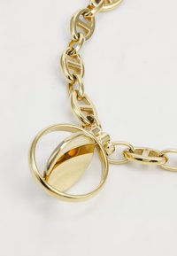 Collar de cadena de oro con eslabones ovalados interconectados, con un colgante circular que presenta una superficie lisa y reflectante y un diseño elegante.