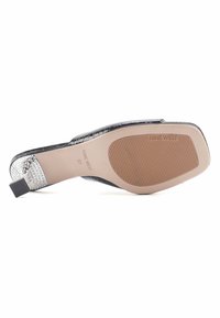 Black leather slingback shoe with a textured upper, shiny silver-accented heel, and a rubber sole featuring horizontal grooves for traction.