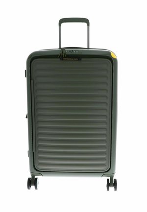 Valise rigide verte avec texture striée, poignée télescopique et quatre roues. Équipée d'un cadenas à combinaison et d'une petite accentuation jaune.