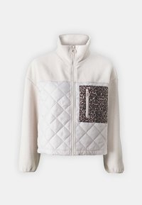 Huppumainen ja tikattu takki kermaisena, jossa vetoketju edessä, korkea kaulus ja leopardikuvioinen rintatasku. Ominaisuuksiin kuuluu teksturoitu kangas ja vetoketjuyksityiskohta.