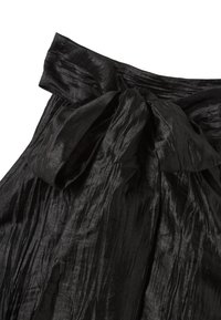 Zwarte hooggewaisted rok van een gestructureerde stof, met een grote strik op de taille en verticale geplooide plooien voor extra detail.