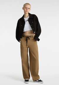 Sort denim cropped jakke, hvid cropped t-shirt med logo, tan vidde bukser med bælte og snore, sorte sneakers.