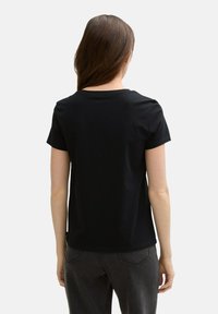 Tricou negru cu mânecă scurtă, cu guler rotund și textură netedă. Vederea din spate arată o croială lejeră și un design minimalist, fără embellishments.