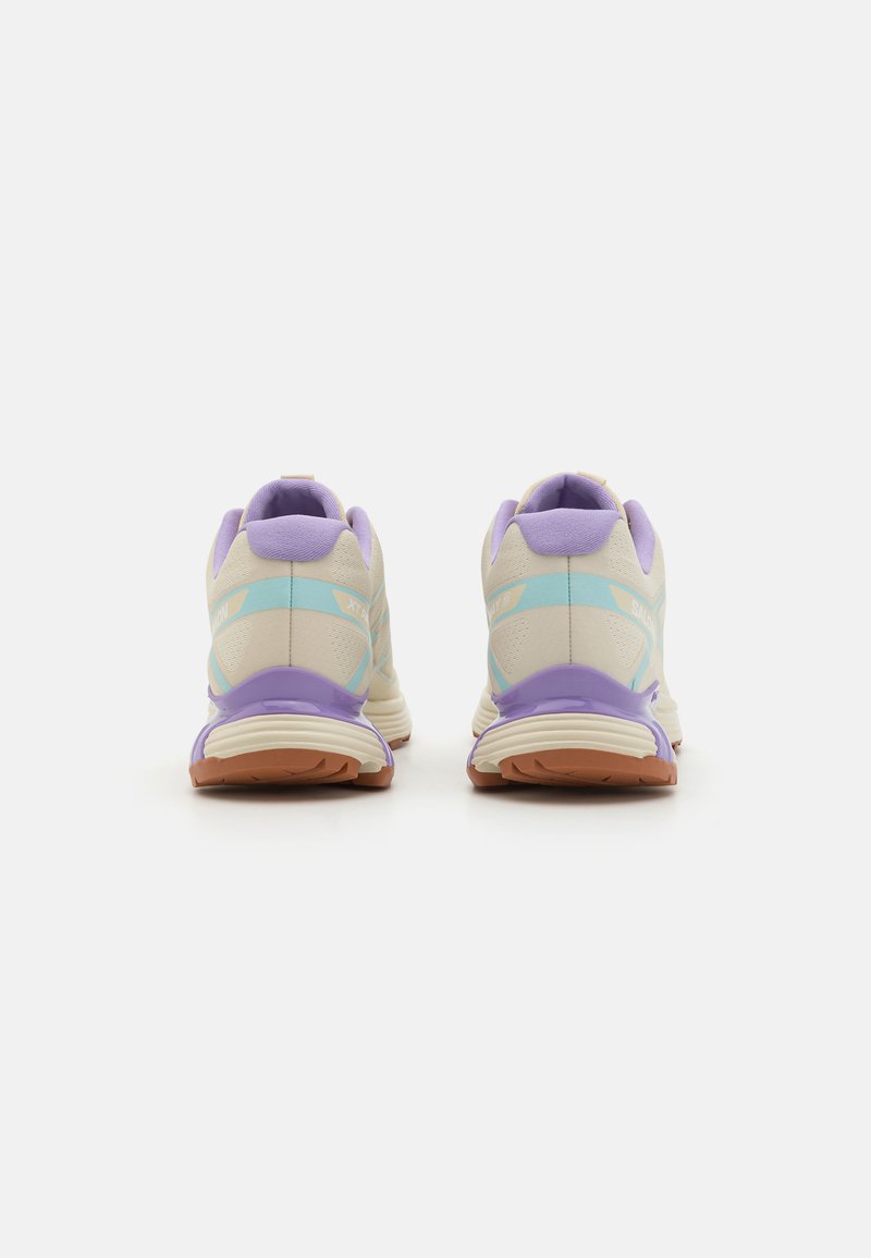 Zapatillas deportivas de color claro con parte superior de malla, acentos en lavanda y suela de goma texturizada. Tacón redondeado y cuello acolchado para mayor comodidad.