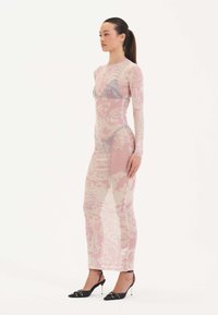 Průhledné šaty s dlouhým rukávem a růžovým a krémovým květinovým vzorem, přiléhavý střih a rovný střih, spojené s černými lodičkami s špičatou špičkou.