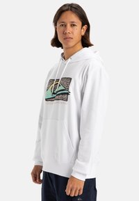 Sudadera blanca hecha de una tela suave, con un diseño gráfico en colores verde azulado, amarillo y negro. Incluye un bolsillo delantero y cordones ajustables.