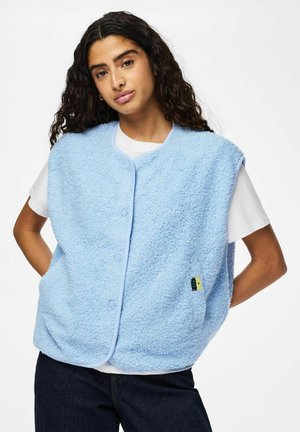 Gilet bleu clair et duveteux en tissu texturé, avec un col rond et des boutons-pression à l'avant. Il possède des poches latérales et une étiquette de marque.