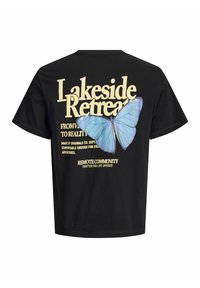 Čierne tričko s veľkým béžovým nápisom "Lakeside Retreat" a modrým motýľom na chrbte. Pod hlavným nápisom je ďalší menší text.