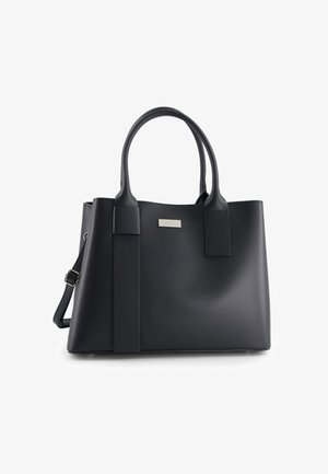 Sac fourre-tout en simili cuir noir avec double anses, une bandoulière réglable et une plaque de marque métallique. Présente une forme structurée et une texture lisse.