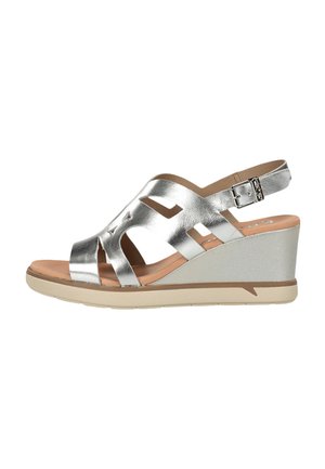 Sandalia cuña metálica plateada con tiras recortadas, hebilla ajustable en el tobillo, plantilla acolchada color canela y suela beige.