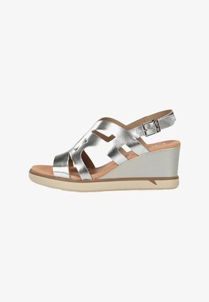 Sandalia cuña metálica plateada con tiras recortadas, hebilla ajustable en el tobillo, plantilla acolchada color canela y suela beige.