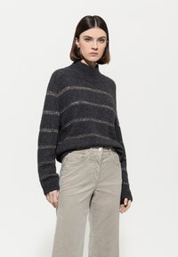 Dunkelgrauer gestrickter Pullover mit hohem Kragen und weiten Ärmeln, der horizontale beige Streifen und ein strukturiertes Muster aufweist.