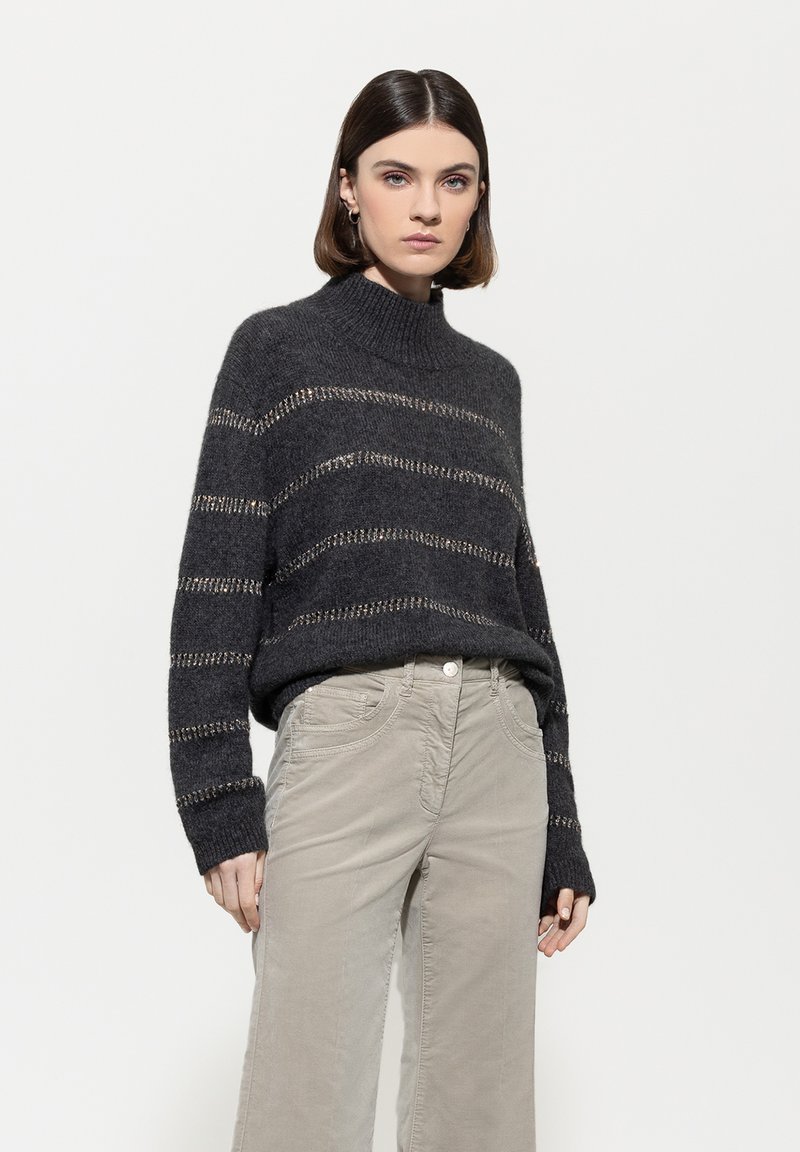 Dunkelgrauer gestrickter Pullover mit hohem Kragen und weiten Ärmeln, der horizontale beige Streifen und ein strukturiertes Muster aufweist.