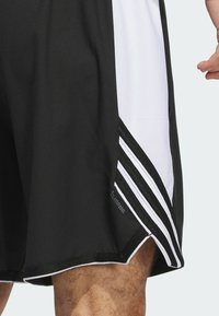 Black athletic shorts featuring white side panels and three black stripes. Made from breathable material with a flat seam finish.