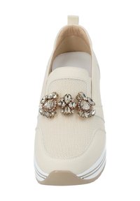 Beiger Slip-On-Sneaker mit strukturiertem Mesh-Obermaterial, glatten Akzenten und dekorativen Juwelenverzierungen an der Vorderseite. Weiße Sohle mit subtilen Streifen.