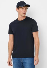 Zwarte t-shirt met korte mouwen en een klassiek ronde hals ontwerp, gemaakt van katoenen stof. Gepaard met een marineblauwe honkbalpet met een blauwe accent.