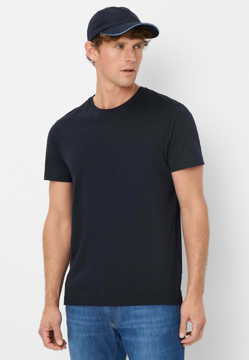 Zwarte t-shirt met korte mouwen en een klassiek ronde hals ontwerp, gemaakt van katoenen stof. Gepaard met een marineblauwe honkbalpet met een blauwe accent.