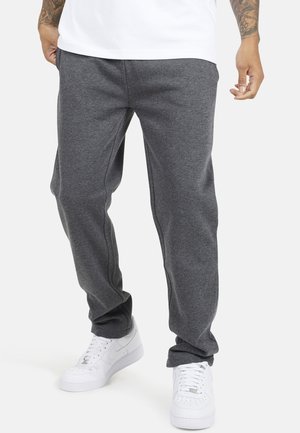 Grijze sweatpants van zachte stof, met een relaxte pasvorm en zijnaad, gecombineerd met witte sneakers. Ontworpen voor comfort en bewegingsvrijheid.