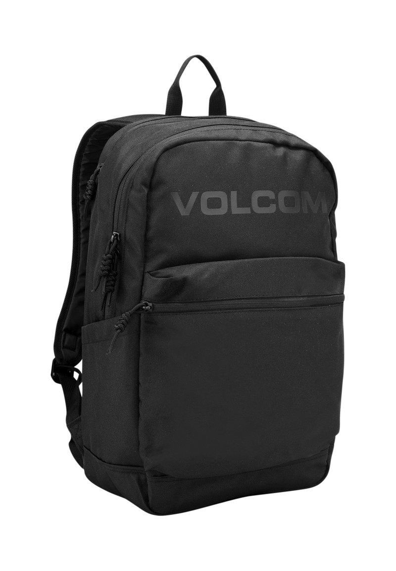 Black backpack with a textured fabric, multiple zippered compartments, and prominent "VOLCOM" logo on the front. Features a top handle.