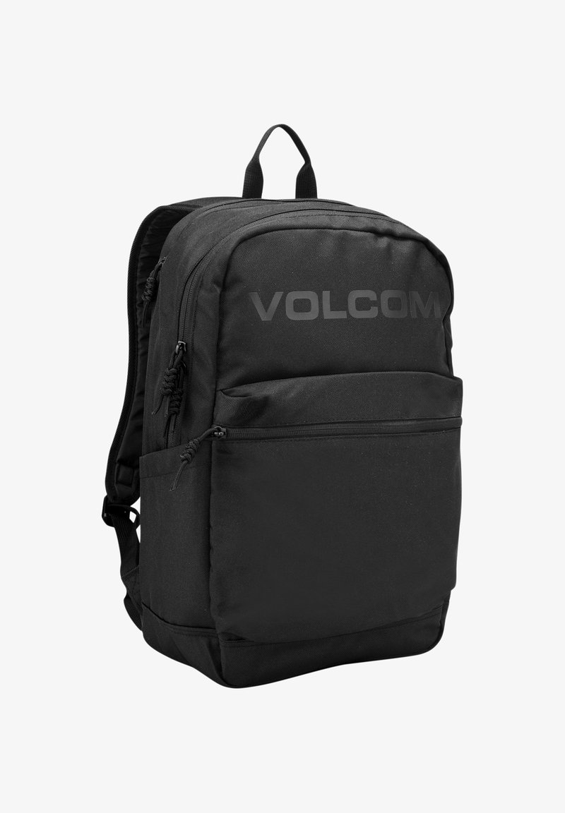 Zwarte rugzak van een textuurachtig materiaal, met meerdere ritscompartimenten en een groot "VOLCOM"-logo op de voorkant. Heeft een handvat aan de bovenkant.