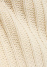 Strickstoff in Cremefarbe mit gerippter Textur, der erhobene diagonale Linien und ein weiches, dickes Aussehen aufweist.