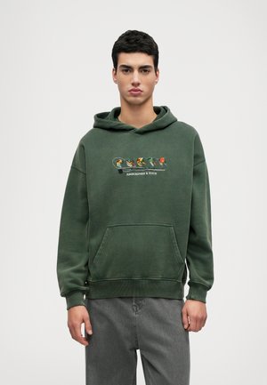 Vihreä huppari, jossa on kengurupockets, nyörihuppu ja brodeerattu monivärinen kuvio, jossa on sarjakuvahahmoja rinnan kohdalla.