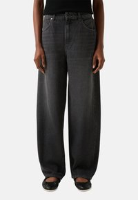 Szerokie dżinsy w kolorze ciemnoszarym z wysokim stanem, przednimi kieszeniami i minimalistycznymi przeszyciami. Tkanina ma gładką teksturę.