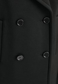 Schwarzer Wollmantel mit doppelter Knopfleiste, auffälligen Revers und zwei schwarzen Knöpfen, der eine glatte Textur und einen maßgeschneiderten Look präsentiert.