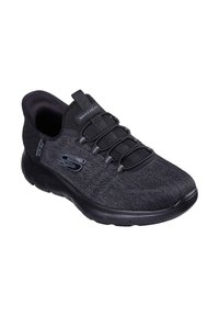 Zapatilla deportiva negra con parte superior de malla texturizada, cordones elásticos y suela acolchada. Presenta un sutil detalle de logo en el lateral.