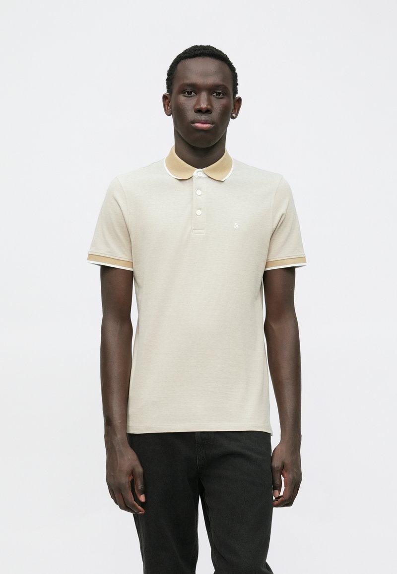 Beige polo shirt med kontrasterende gul krage og ermebesetning, med en tre-knaps placket og en liten logo på brystet.